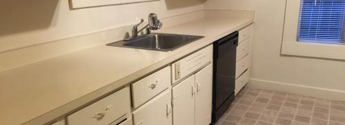 Kitchen shows white counterspace and metal sink.