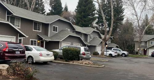 Several grey connected townhomes with cars parked in front.